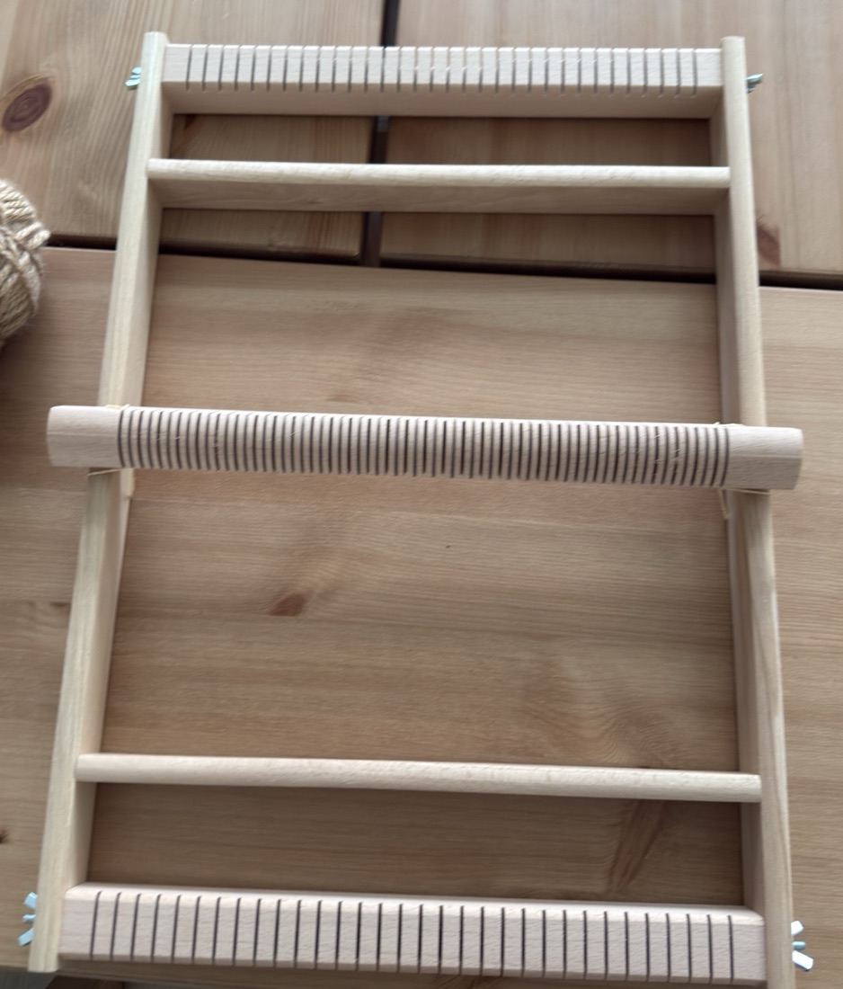 Stanley's wooden loom from above: a notched beam at the top and bottom, a grooved roller across the middle, two plain crossbars, and wing nuts at the corners